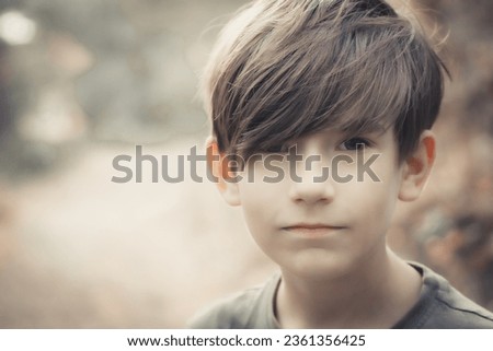 The boy is looking at the photo camera. A child enjoys nature in the forest. Soft selective focus