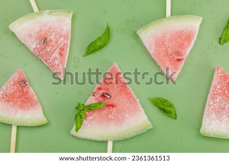 Frozen watermelon popsicles on trendy Savannah green background. Refreshing summer dessert, flat lay, top view