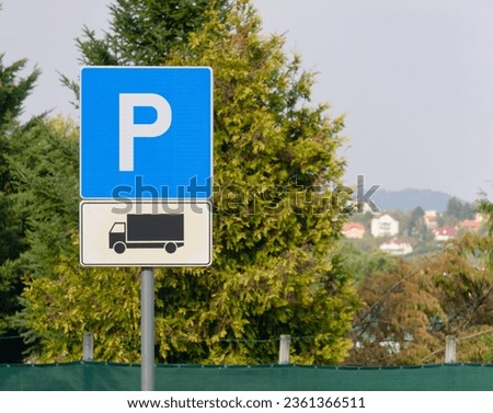 Close-up photo of a Truck parking sign on a metal pole with a tree and sky in the background
