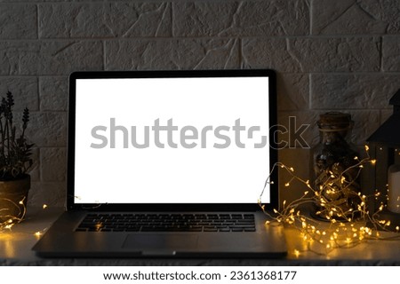Front view of the laptop with mockup screen on the desk. Christmas gifts and decorations behind laptop. Holiday online shopping or sale. Internet goods. Copy space. Reindeer, Christmas tree.