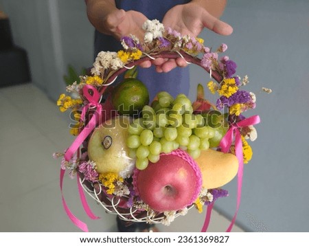 very beautiful fruits and flowers basket for someone you love special gift, red big apple, big trolley, green oranges, green grapes,yellow, white ,purple flowers and tie with pink ribbon  