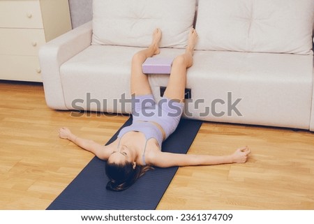 A girl is doing fitness at home near the sofa.