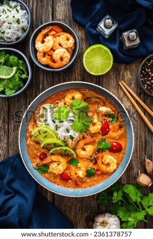 Tom Yum soup - Thai soup with prawns and rice noodles on wooden table Royalty-Free Stock Photo #2361378757