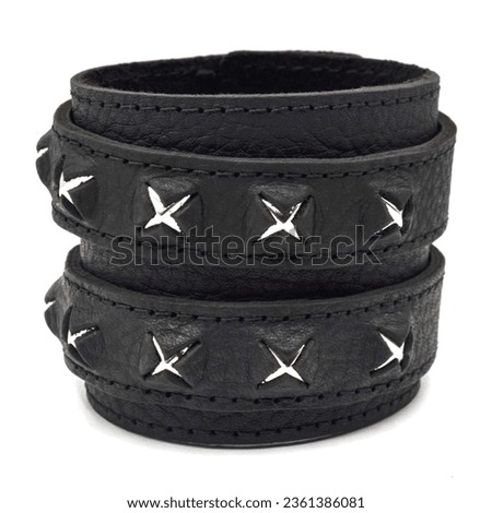 Black leather bracelet with spikes, pyramids. An accessory for rockers, bikers, metalheads, goths and punks. Steampunk style. Close-up subject photography.