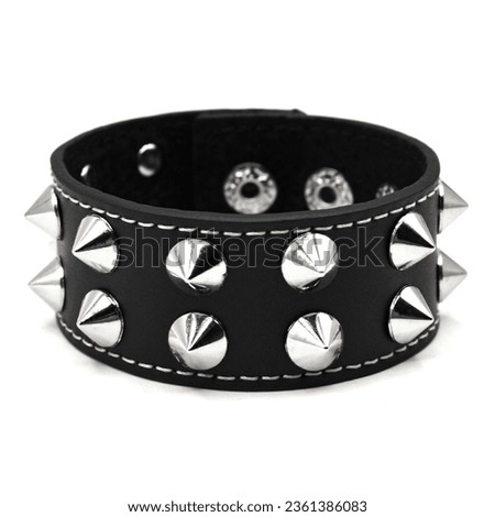 Black leather bracelet with spikes, holnitenes. An accessory for rockers, bikers, metalheads, goths and punks. Steampunk style. Close-up subject photography. Royalty-Free Stock Photo #2361386083