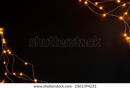 Christmas lights garland border over black background. Flat lay, copy space.