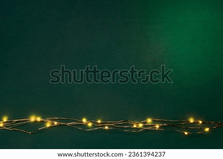 Christmas lights garland border over green background. Flat lay, copy space.