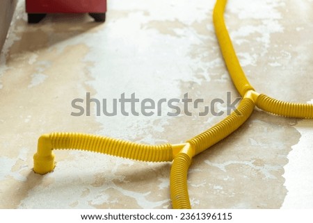 Water damage restoration service pipes in a leaking home environment connected to industrial air movers and dehumidifiers to remove the water and moist from the wet floor. Household insurance Royalty-Free Stock Photo #2361396115