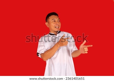 Adult Asian man showing excited expression while pointing to the left side
