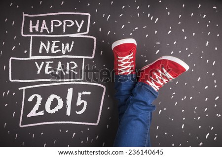 Happy new year 2015. Christmas concept with red sneakers and white chalk text on black floor