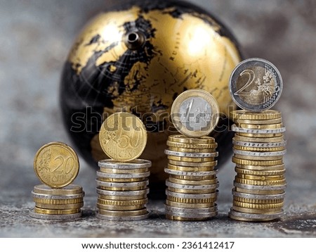 stacks of euro and cent coins symbolize a price increase in front of a black and gold globe, concept of money increase, international inflation or global stock trading Royalty-Free Stock Photo #2361412417