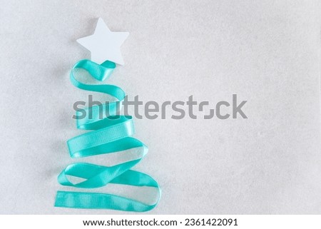 Christmas tree made of turquoise ribbon and star on white background
