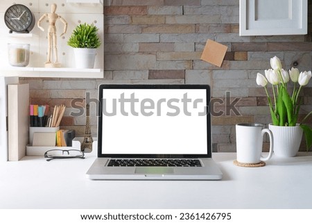 Laptop computer, picture frame, houseplant and stationery on white table. Modern workplace.
