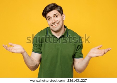 Young sad caucasian man he wearing green t-shirt casual clothes spreading hands hrugging shoulders looking puzzled, have no idea isolated on plain yellow background studio portrait. Lifestyle concept