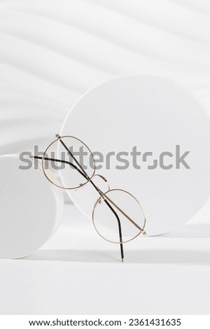 Unisex eyeglasses in a golden metallic frame on a podium on white background. Vertical, close up. The product minimal still life. Optic store discount, sale. Copy space. Trendy eyewear photography