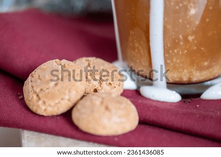Three cookies next to a cup of coffee with melted and drained cream on a red napkin. Copy space. High quality photo