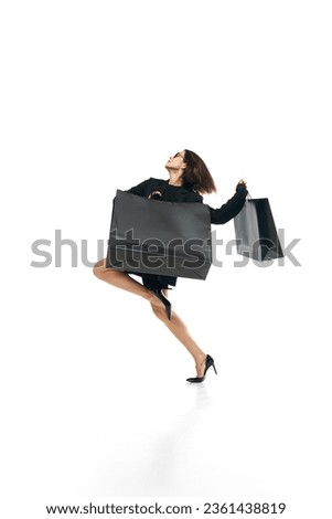 Shopaholic. Full lenth portrait of young woman wearing officilly outfit enjoying shopping, purchases and running with huge bags. Concept of Black Friday, Cyber monday, fashion, beauty, buying, sales. Royalty-Free Stock Photo #2361438819
