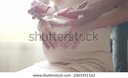 Pregnant couple husband and wife. family pregnancy expecting baby concept. man taking care of pregnant mother. baby shoes lifestyle on belly of pregnant woman husband hugs belly guards takes care