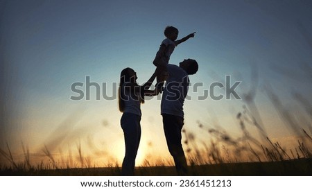 happy family in the park. father and mother raise son up play play with child silhouette. happy family kid dream concept. friendly family playing with baby outdoors in lifestyle the park