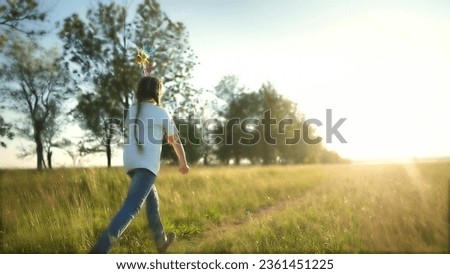 baby pinwheel. little girl silhouette plays with windmill toy wind in the park. happy family childhood dream concept. girl play spinner toy glare of the sun at sunset in cheerful park fun Royalty-Free Stock Photo #2361451225