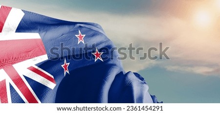 New Zealand national flag cloth fabric waving on beautiful sky Background.