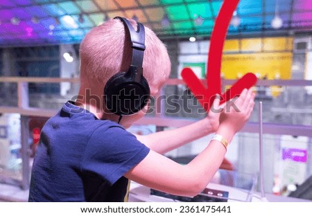 Boy with headphones. Blond man listens to music in public places. Noise suppression device. The concept of holding an individual lecture, caring for others, a quiet party and a training program Royalty-Free Stock Photo #2361475441