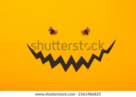 Decorative spiders and paper mouth on yellow background, top view