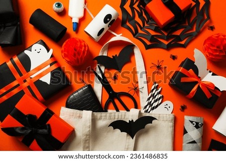 Gift boxes, scissors, cotton bag and paper halloween mockups on orange background, top view