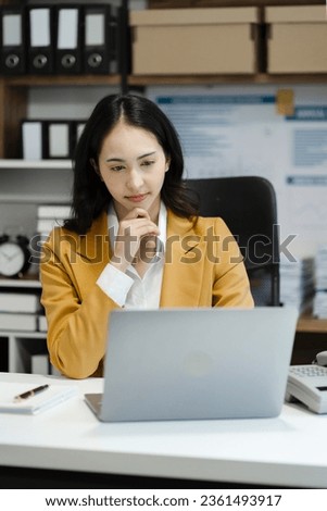 business woman sitting at her desk, reading stats and graphs on paperwork at the office.
