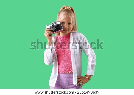 Little girl with photo camera on green background