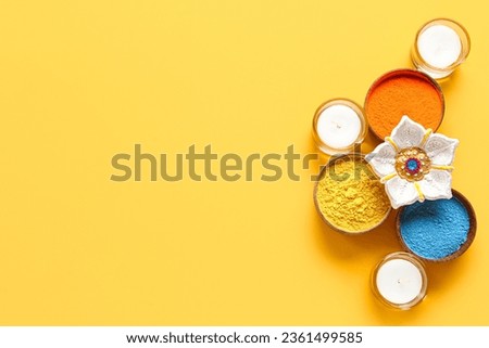 Diya lamp with candles and bowls of colorful powder on yellow background. Divaly celebration Royalty-Free Stock Photo #2361499585