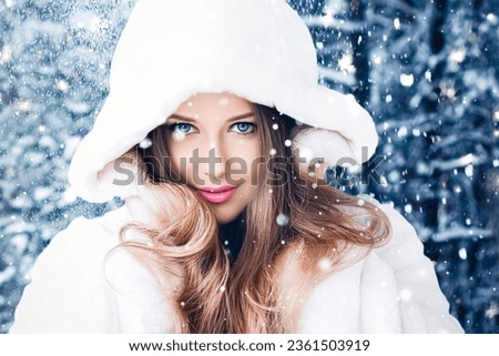 Happy holidays, lifestyle and winter fashion, beautiful woman wearing white fluffy fur coat, snowing snow in snowy forest nature as Christmas, New Year and holiday portrait style Royalty-Free Stock Photo #2361503919