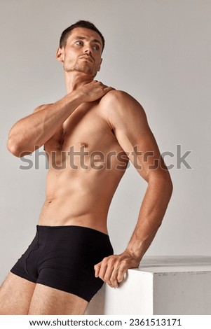 Portrait of handsome man with muscular, athletic body shape posing shirtless in underwear against grey studio background. Concept of men's health and beauty, body care, fitness, wellness, ad Royalty-Free Stock Photo #2361513171