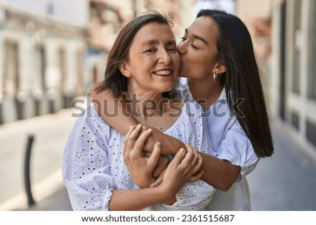 Two women mother and daughter hugging each other kissing at street