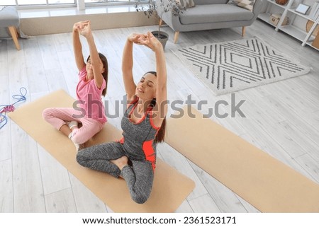 Sporty mother with her little daughter training at home