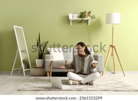 Beautiful happy young woman with laptop video chatting  in living room Royalty-Free Stock Photo #2361523299