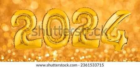 golden number helium balloons 2024 against bokeh.