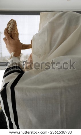 Man blowing the Shofar (horn) of Rosh Hashanah (New Year) and Yon Kippur (Day of atonement)  . Jewish Religious symbol. Royalty-Free Stock Photo #2361538933