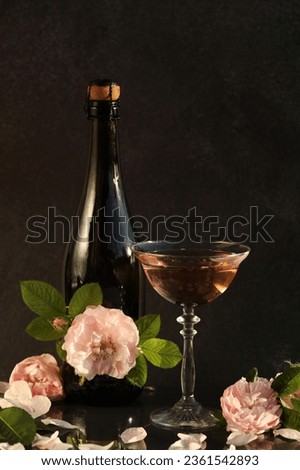 Glass of pink champagne with rose flowers on the black background