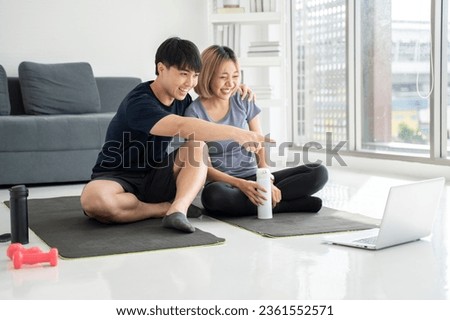 Couple resting after exercising at home Watch sports videos online Point to the screen Talk about exercise