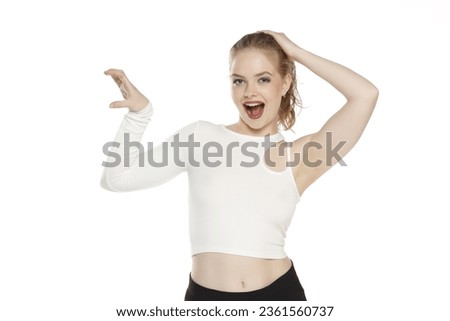 Young happy excited blonde woman with tied hair  over isolated white studio background holding copyspace imaginary object on the palm to insert an ad