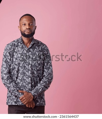 A studio picture of a man in african print looking into camera. 