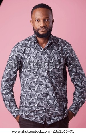 A studio picture of a man in african print looking into camera. 