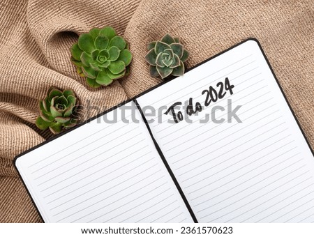 Notebook with hello 2024 handwritten on rustic surface with succulents