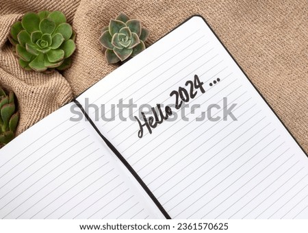 Notebook with hello 2024 handwritten on rustic surface with succulents Royalty-Free Stock Photo #2361570625