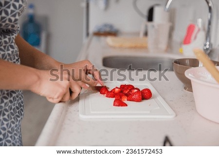 girl cook cuts strawberries close-up