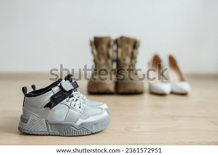 Old worn military boots, women's shoes and baby shoes on wooden floor. Veteran and family concept