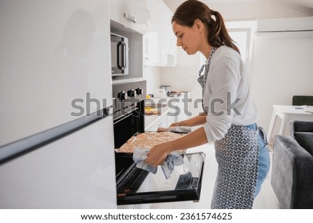 girl puts a baking sheet in the oven