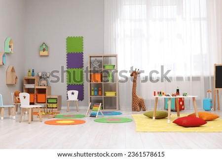 Child`s playroom with different toys and furniture. Cozy kindergarten interior Royalty-Free Stock Photo #2361578615