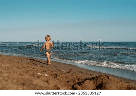 little boy 3 years old plays in the sand on the beach near the s